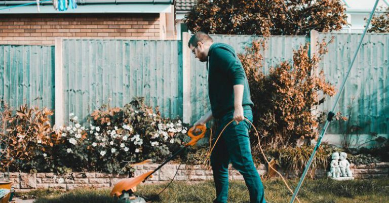 Chores - Man Holding Orange Electric Grass Cutter on Lawn